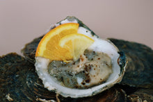 Load image into Gallery viewer, Mersea Oyster on a half shell with a slice of lemon on a textured surface