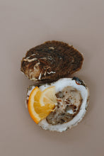 Load image into Gallery viewer, Open native oyster with lemon wedge on a beige background