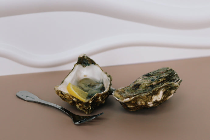 Open Jersey oyster with lemon wedge on a brown surface with a white cloth background