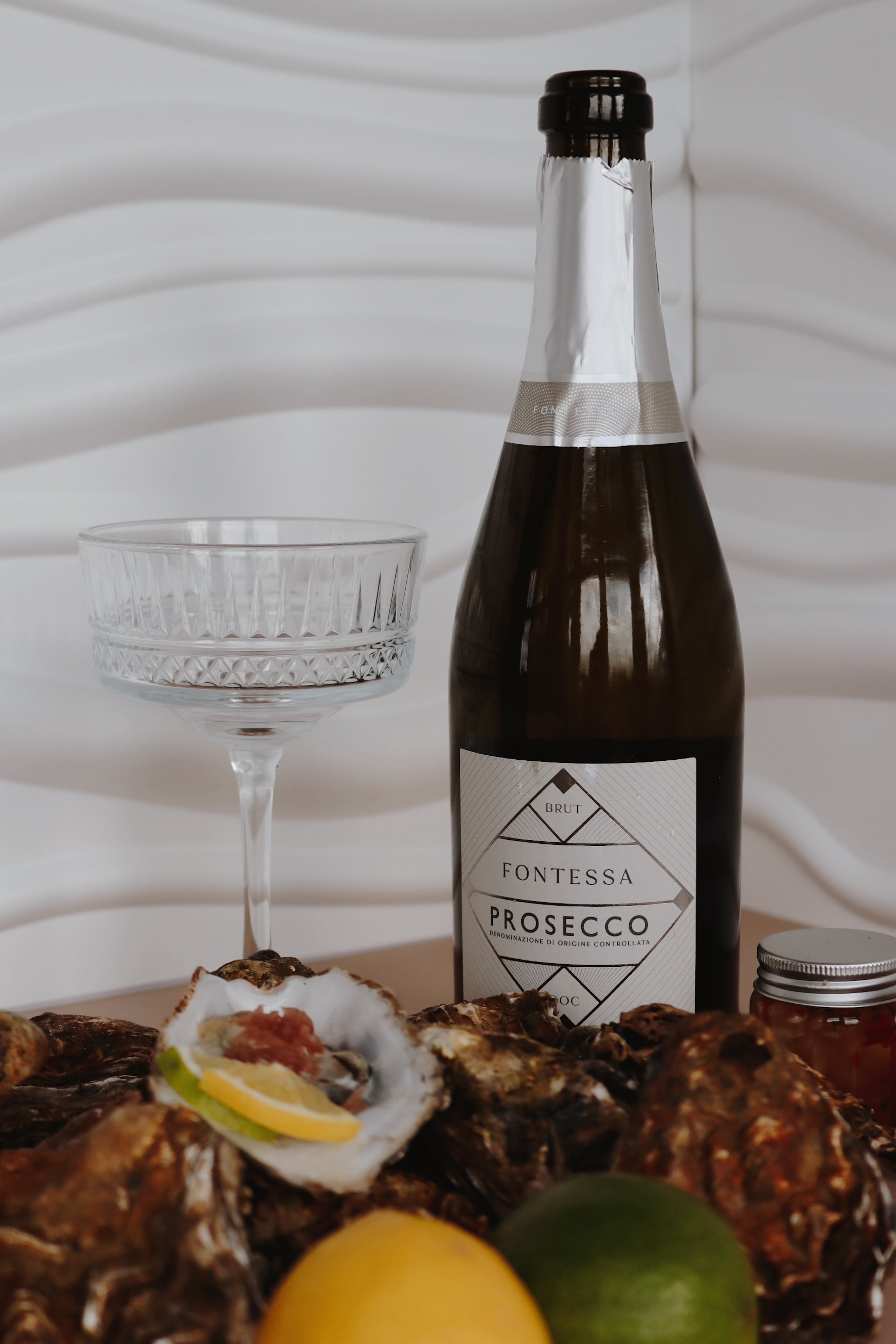 Bottle of Fontessa Prosecco with Mersea oysters and fruit on a table