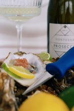 Load image into Gallery viewer, Mersea rock Oysters on a half shell with lemon wedges, a bottle of Fontessa Prosecco, and a glass of white wine. Square handled shucking knife. 