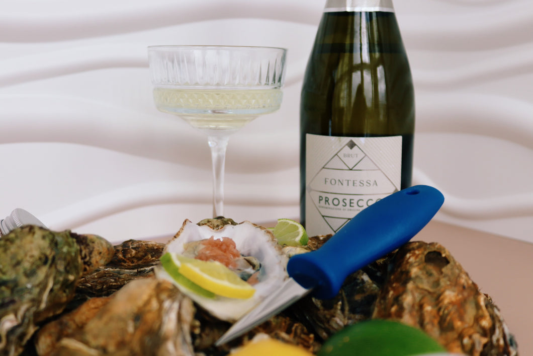 Mersea Oysters on a plate with a bottle of Fontessa Prosecco and a glass of white wine with an oyster shucking knife 