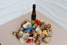 Load image into Gallery viewer, Mersea Oysters on the half shell with a bottle of wine and condiments on a white surface